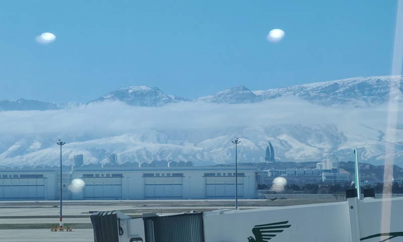 Aerial view of Ashgabat's white marble skyline with the Kopet Dag mountains in the background at golden hour taken from Ashgabat International Airport