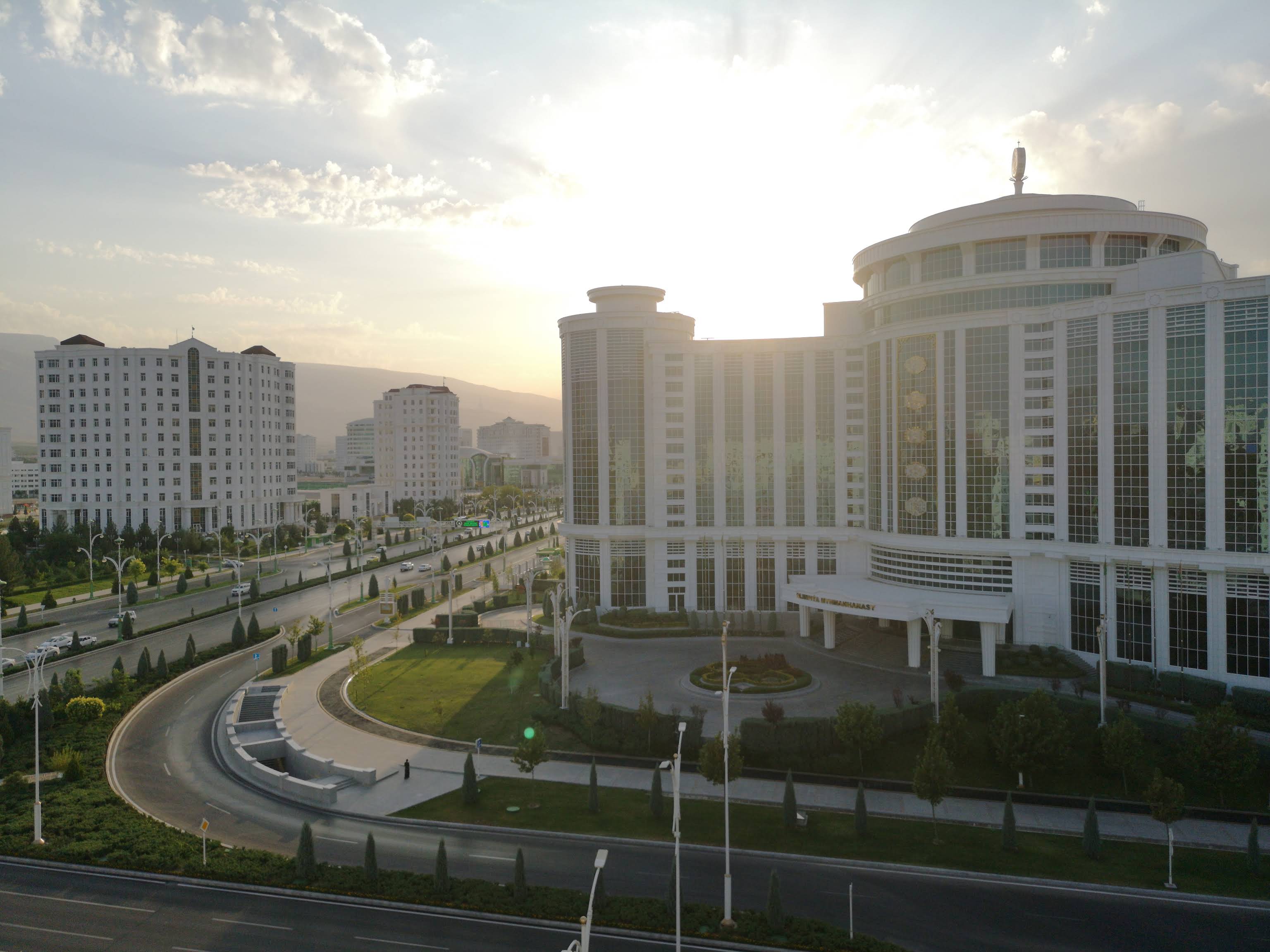 Breiter Boulevard in Aschgabat, gesaumt von weissen Marmorregierungsgebauden, die helles Sonnenlicht unter einem klaren blauen Himmel reflektieren