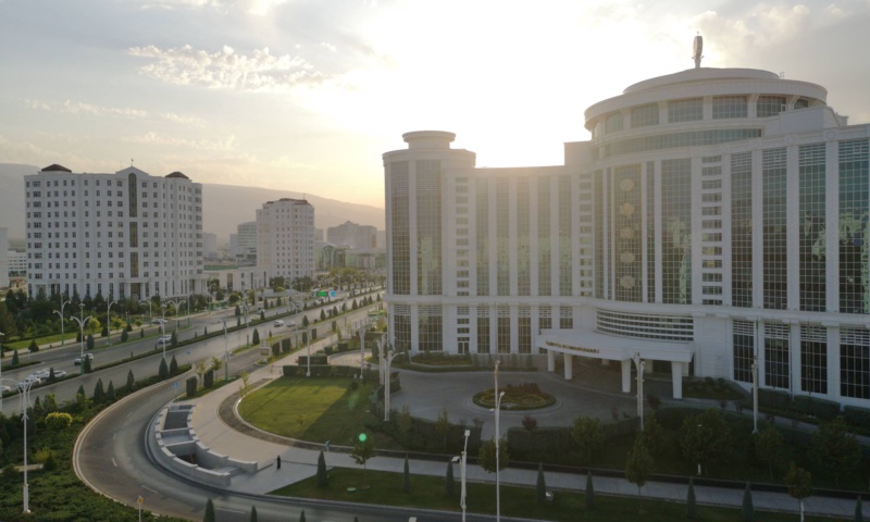 Breiter Boulevard in Aschgabat, gesaumt von weissen Marmorregierungsgebauden, die helles Sonnenlicht unter einem klaren blauen Himmel reflektieren